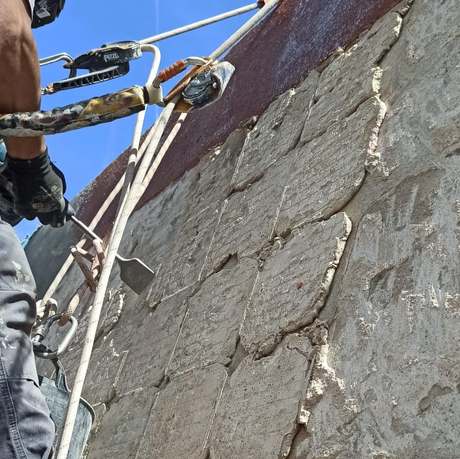 Un hombre está trabajando en una pared con una herramienta que dice Petzl.