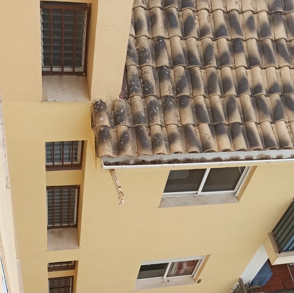 Un edificio amarillo con techo de tejas y ventanas