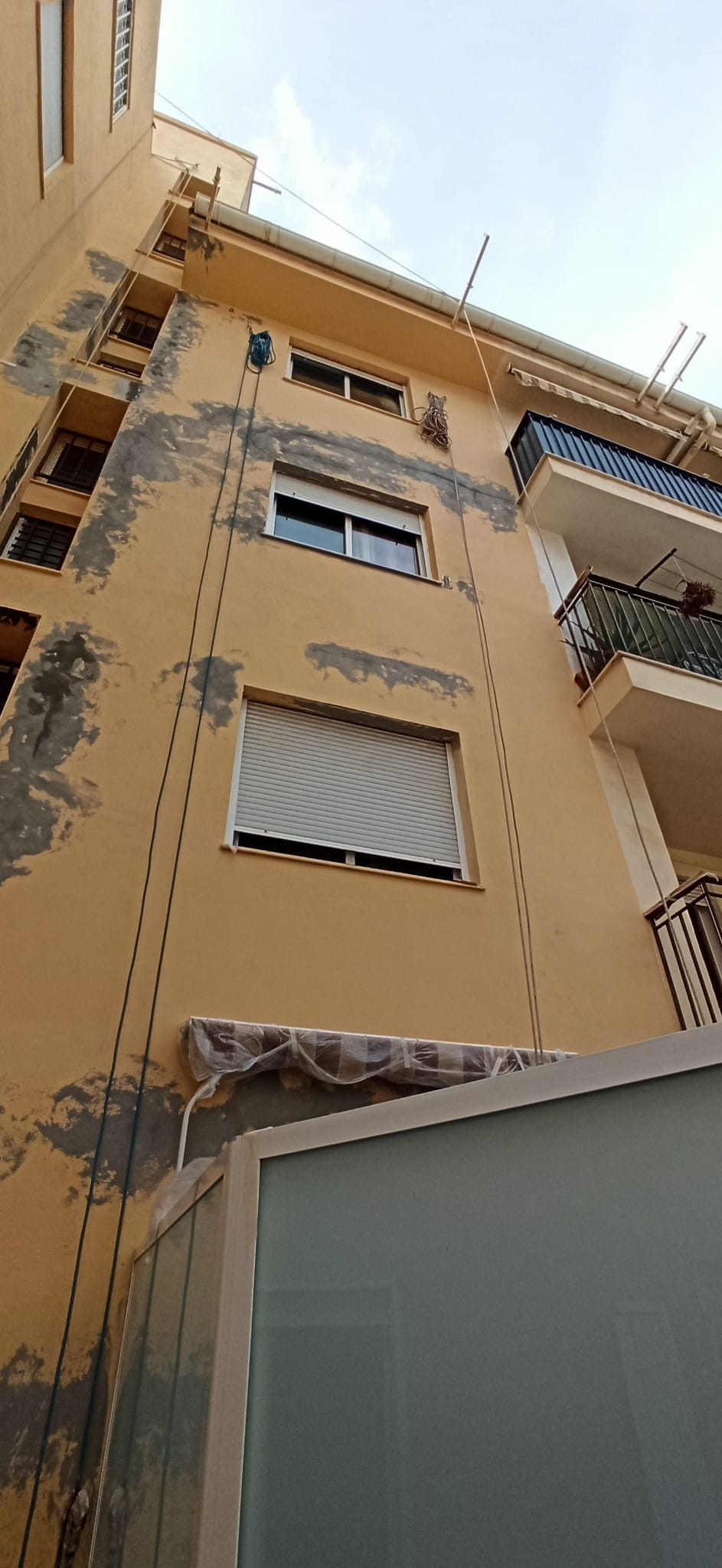 Un edificio amarillo con muchas ventanas y balcones.