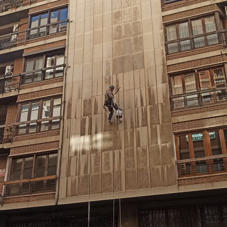 Un hombre está subiendo por el costado de un edificio.