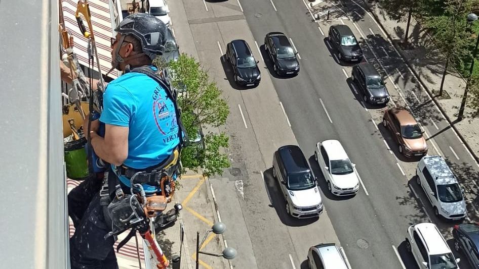 Un hombre está parado en la parte superior de un edificio al lado de una calle concurrida.