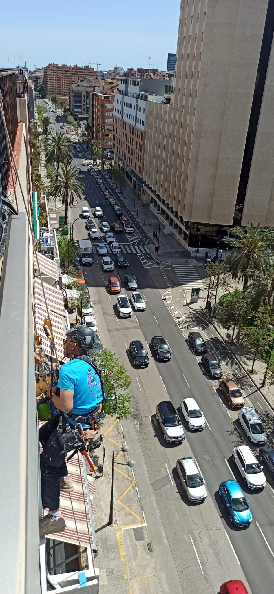 Un hombre está de pie en un balcón con vistas a una concurrida calle de la ciudad.