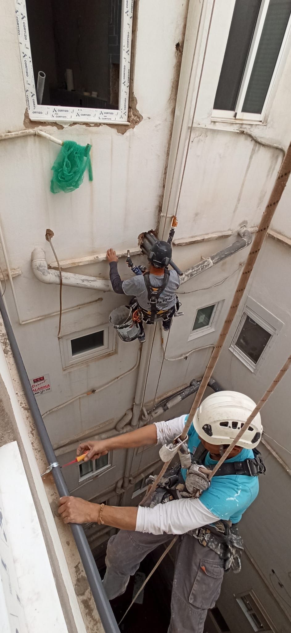 Un hombre está trabajando en una tubería en el costado de un edificio.