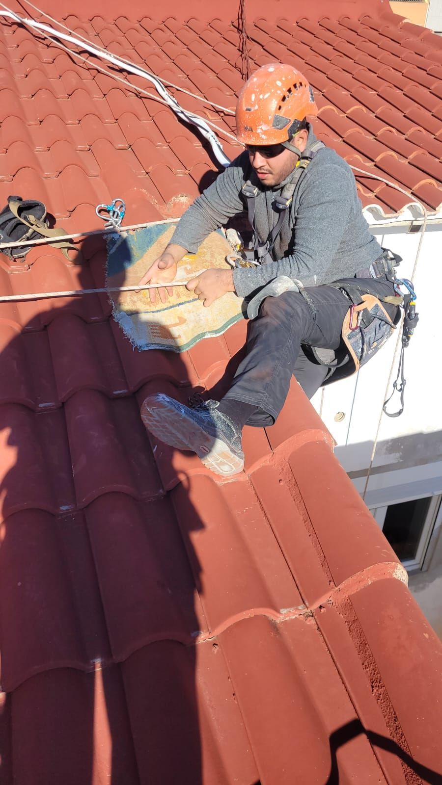 Un hombre está sentado encima de un techo de tejas rojas.