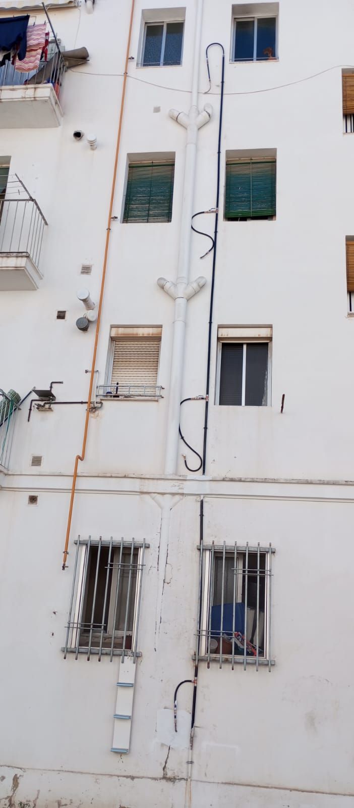 Un edificio blanco con una escalera al costado.