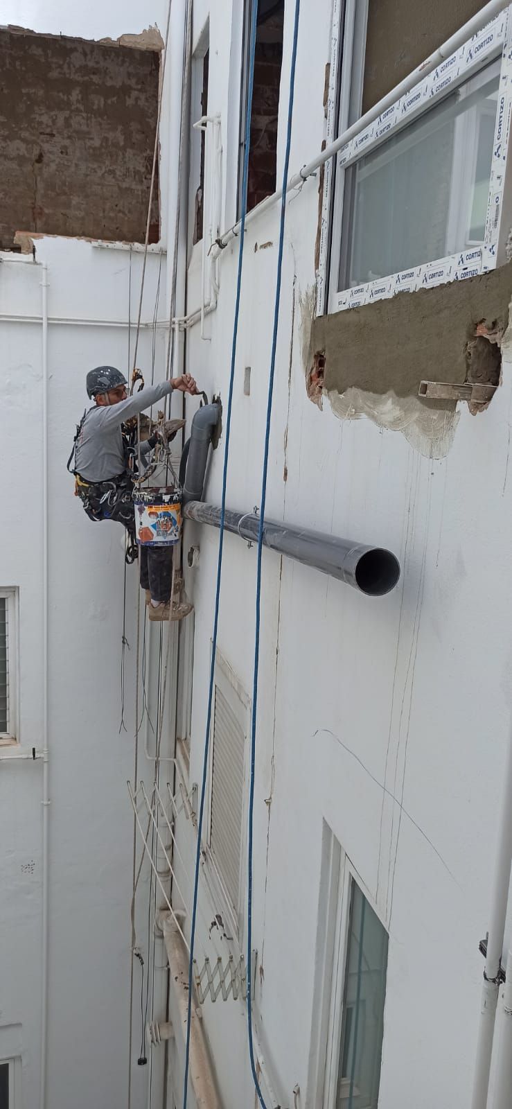 Un hombre está trabajando en el costado de un edificio.