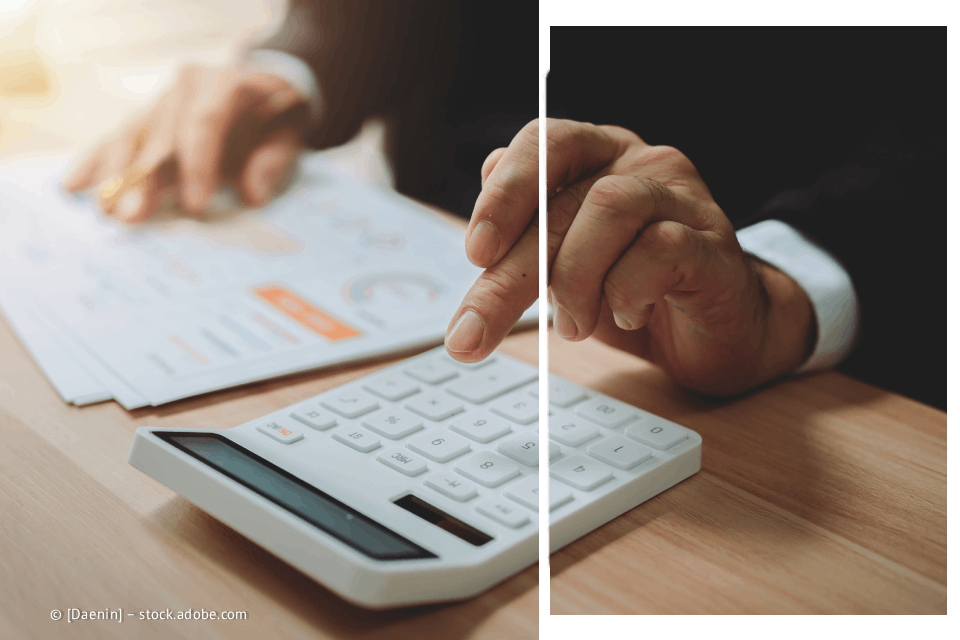 Person, die einen Taschenrechner verwendet und Dokumente auf einem Schreibtisch überprüft.