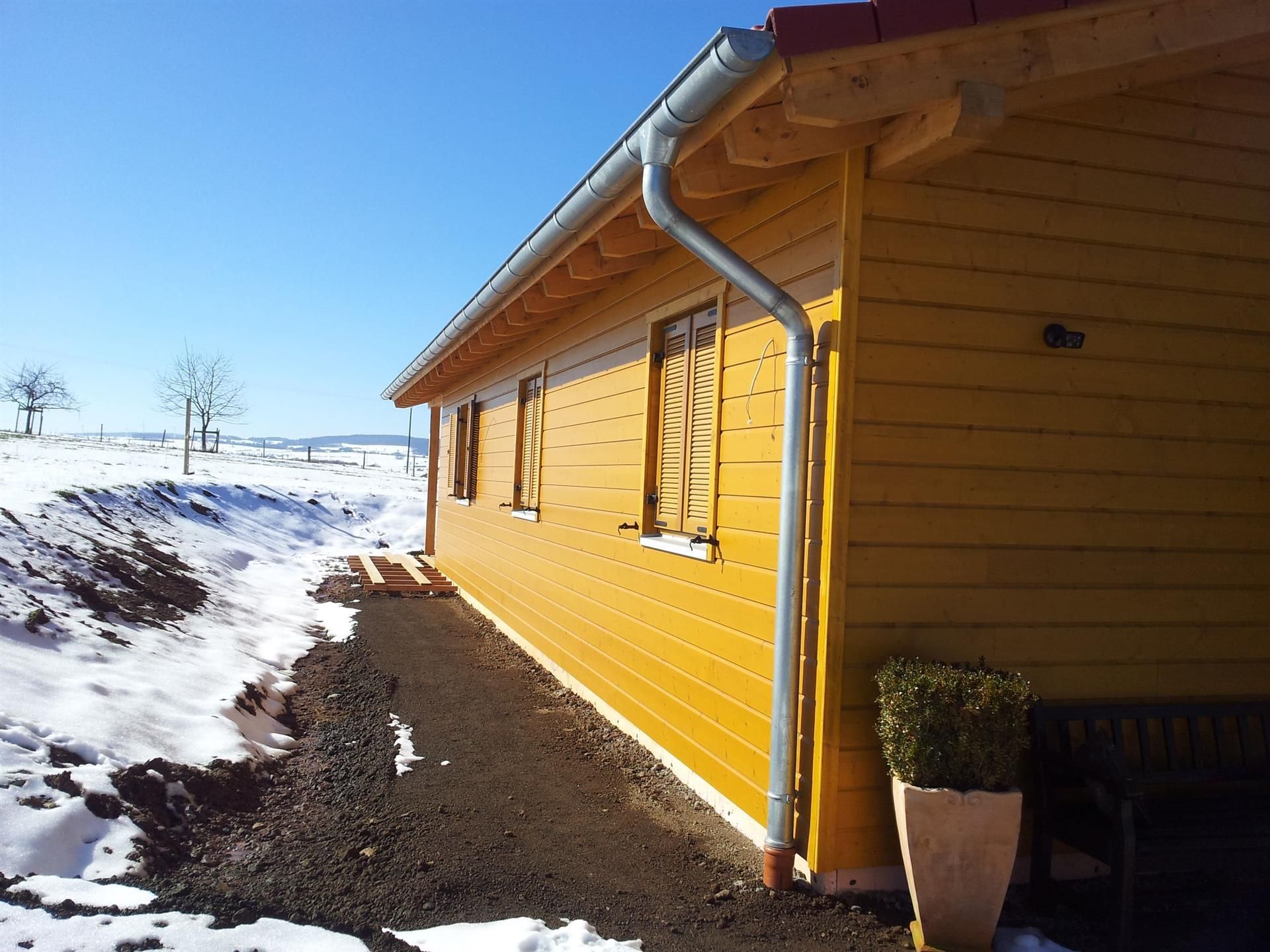 Ein gelbes Haus mit Schnee auf dem Boden davor