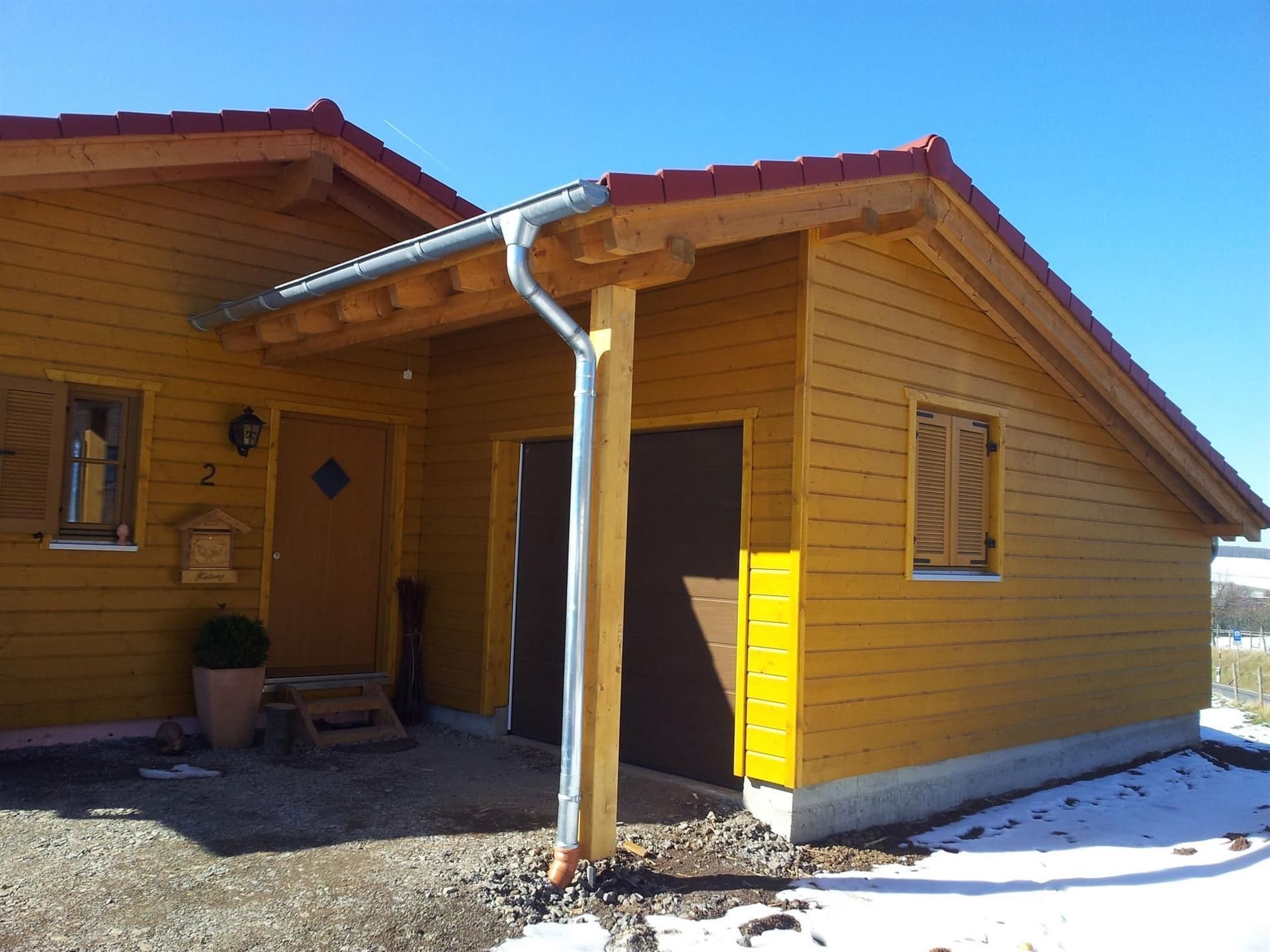 Ein gelbes Haus mit rotem Dach und einem Briefkasten