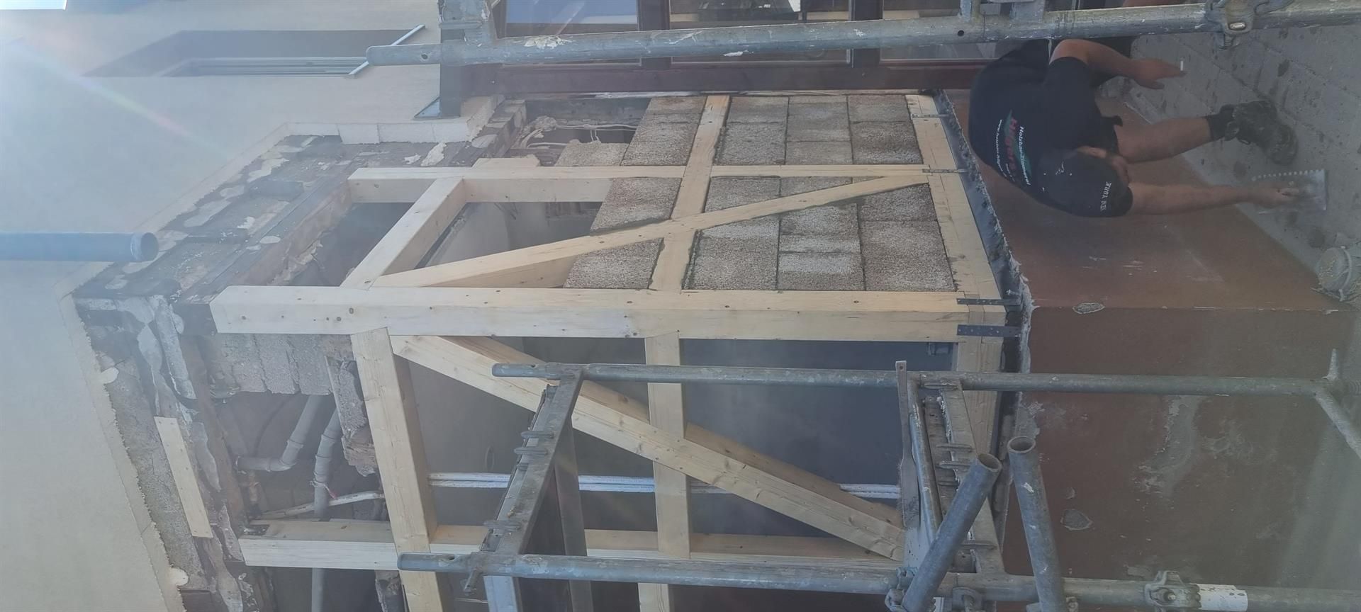 Ein Mann arbeitet an einer Holzkonstruktion in einem Gebäude.