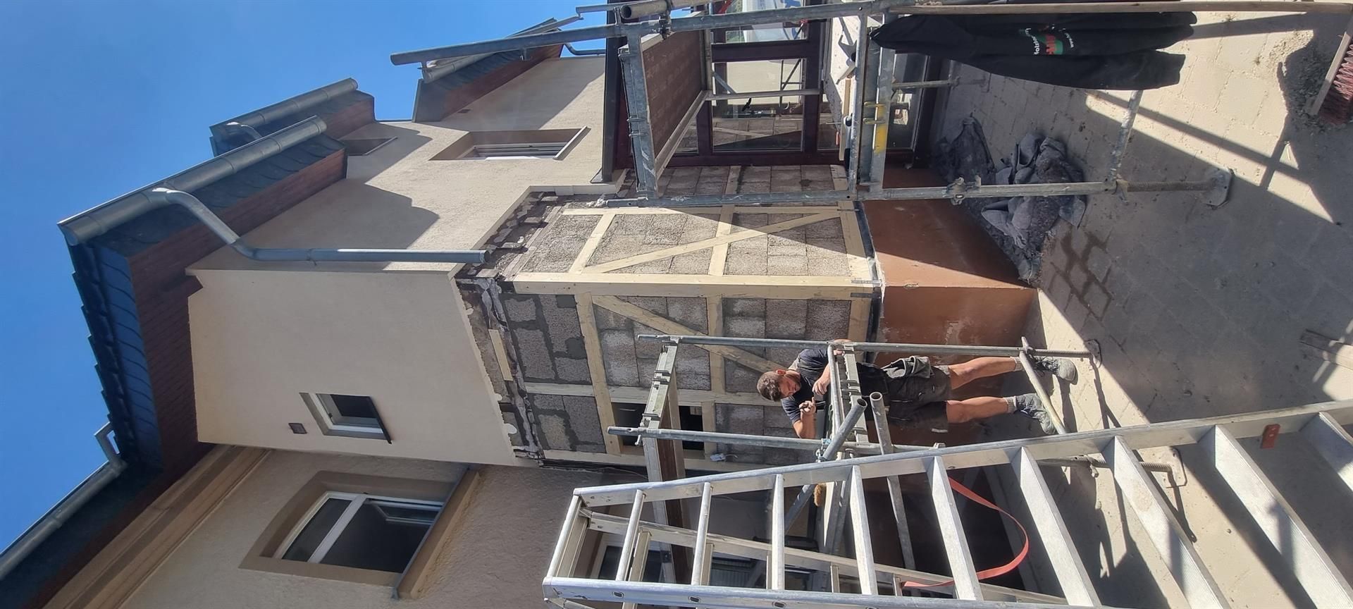 Ein Mann steht auf einer Leiter vor einem Gebäude