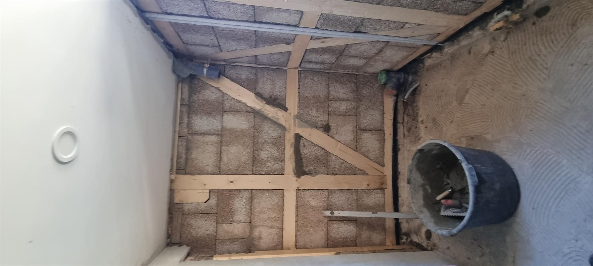 In der Mitte des Raumes steht ein Eimer Zement.