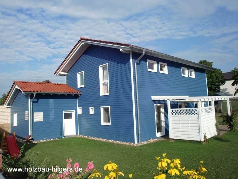 Ein blaues Haus mit der Website www.holzbau hilgers.de auf der Unterseite