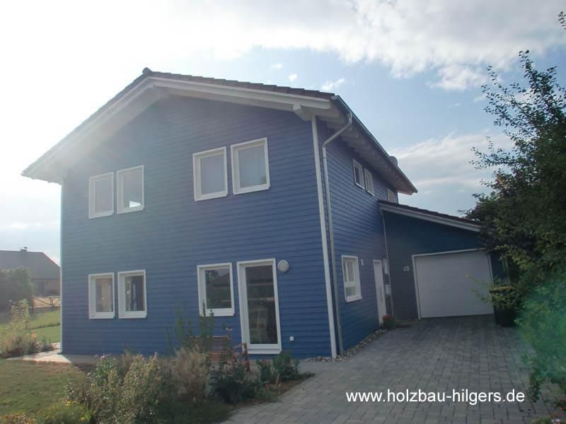 Ein blaues Haus mit der Website www.holzbau-hilgers.de unten