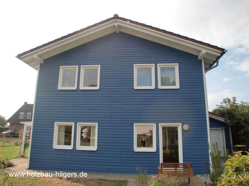 Ein Bild von einem blauen Haus mit weißen Zierleisten und Fenstern