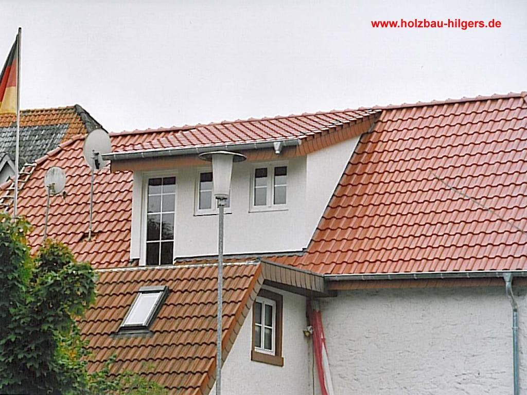 Ein weißes Haus mit einem roten Ziegeldach und einem Fenster