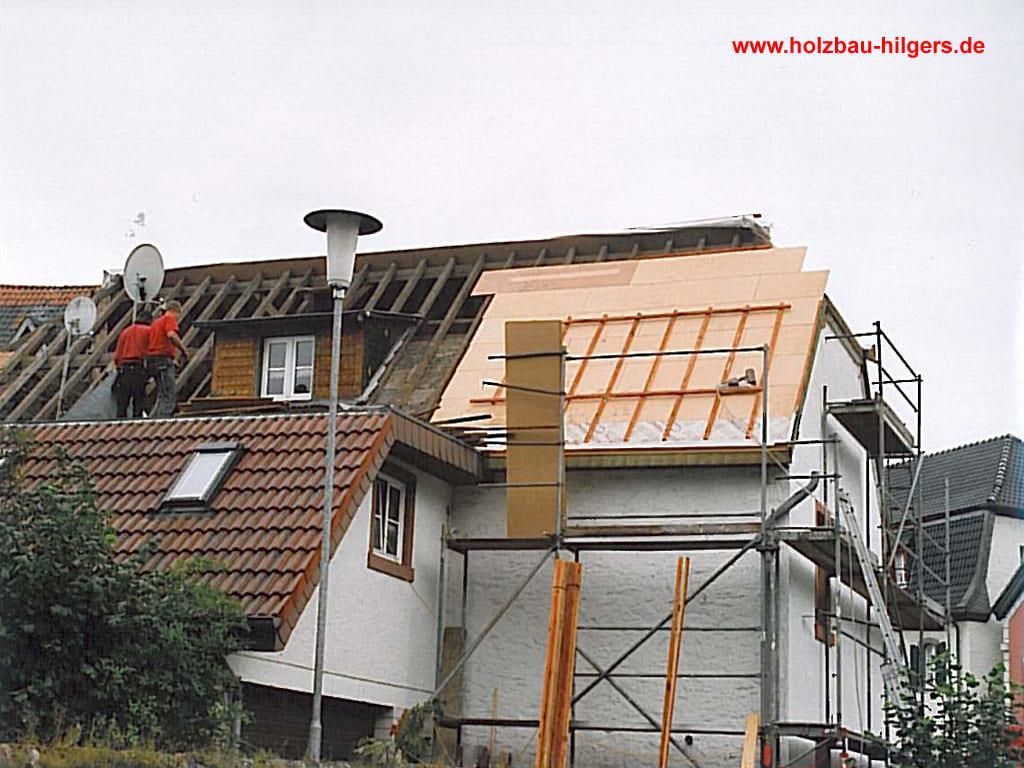 Ein Mann arbeitet auf dem Dach eines Hauses und die Website ist www.holzbau-hilfen.de