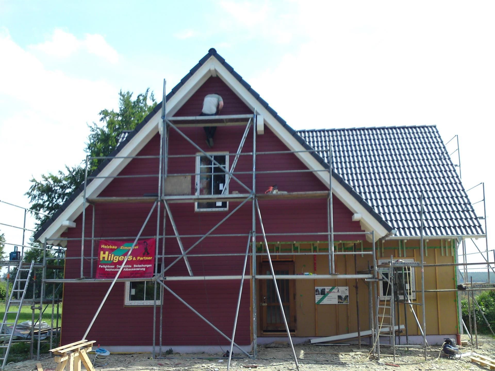 Ein rotes Haus wird mit Gerüsten darum herum gebaut