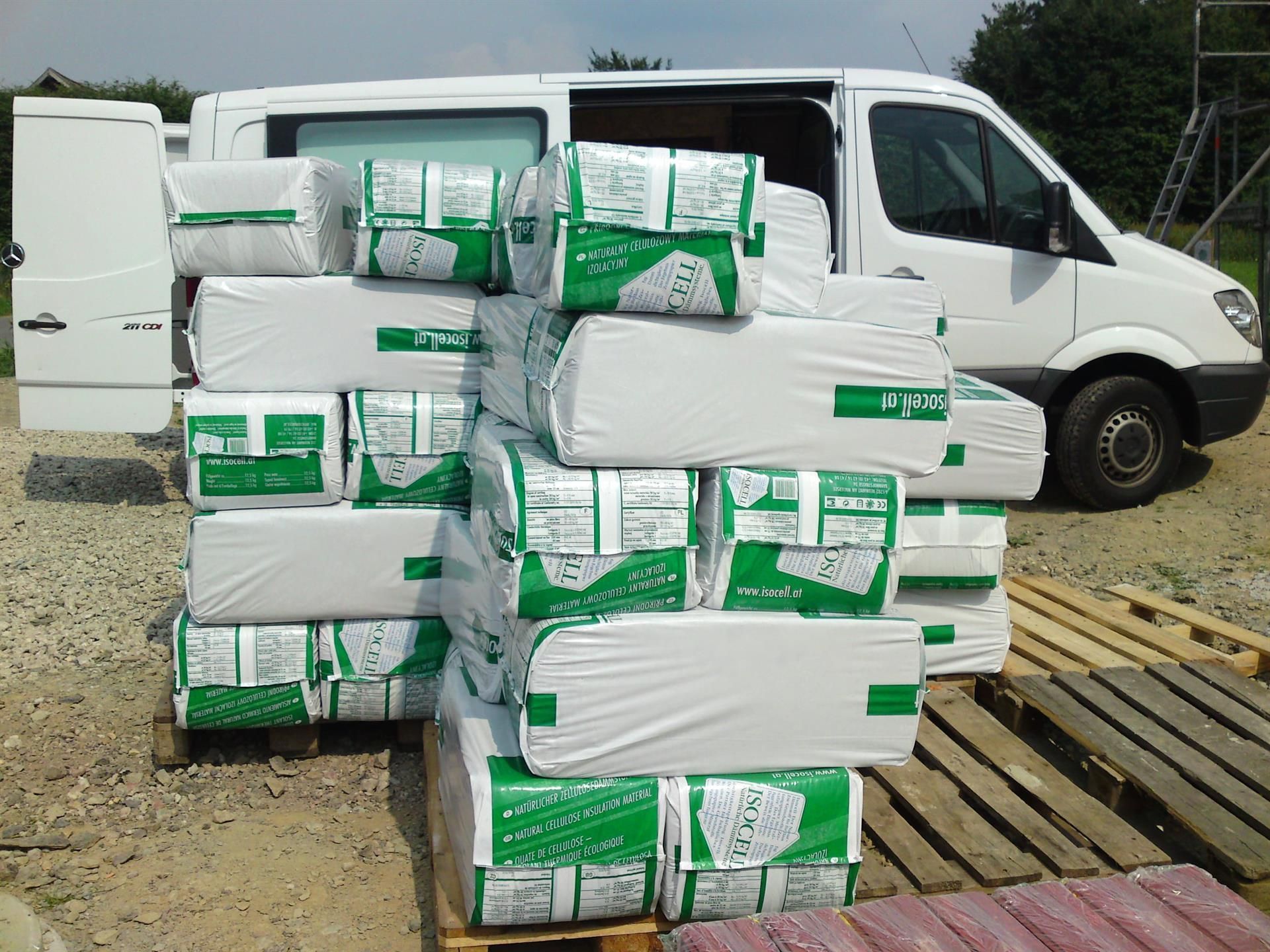 Ein weißer Lieferwagen steht neben einem Stapel grün-weißer Kisten