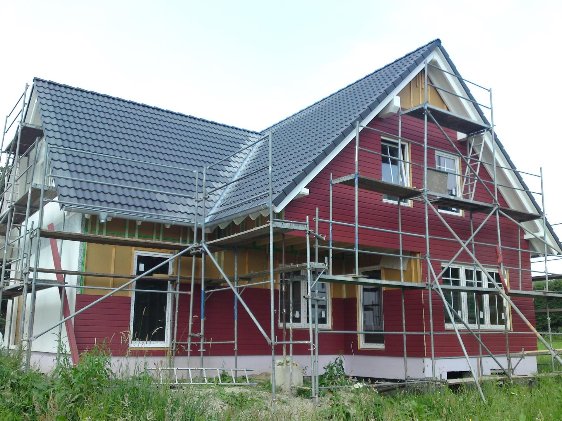 Ein rotes Haus mit Gerüsten darum herum ist im Bau