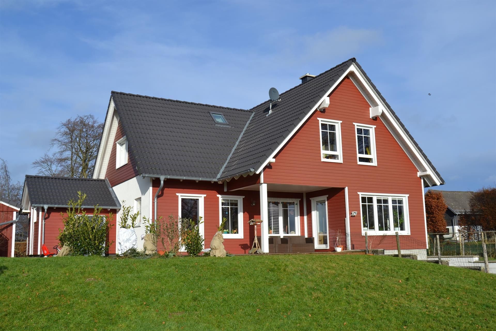 Ein rotes Haus mit schwarzem Dach und weißen Verzierungen