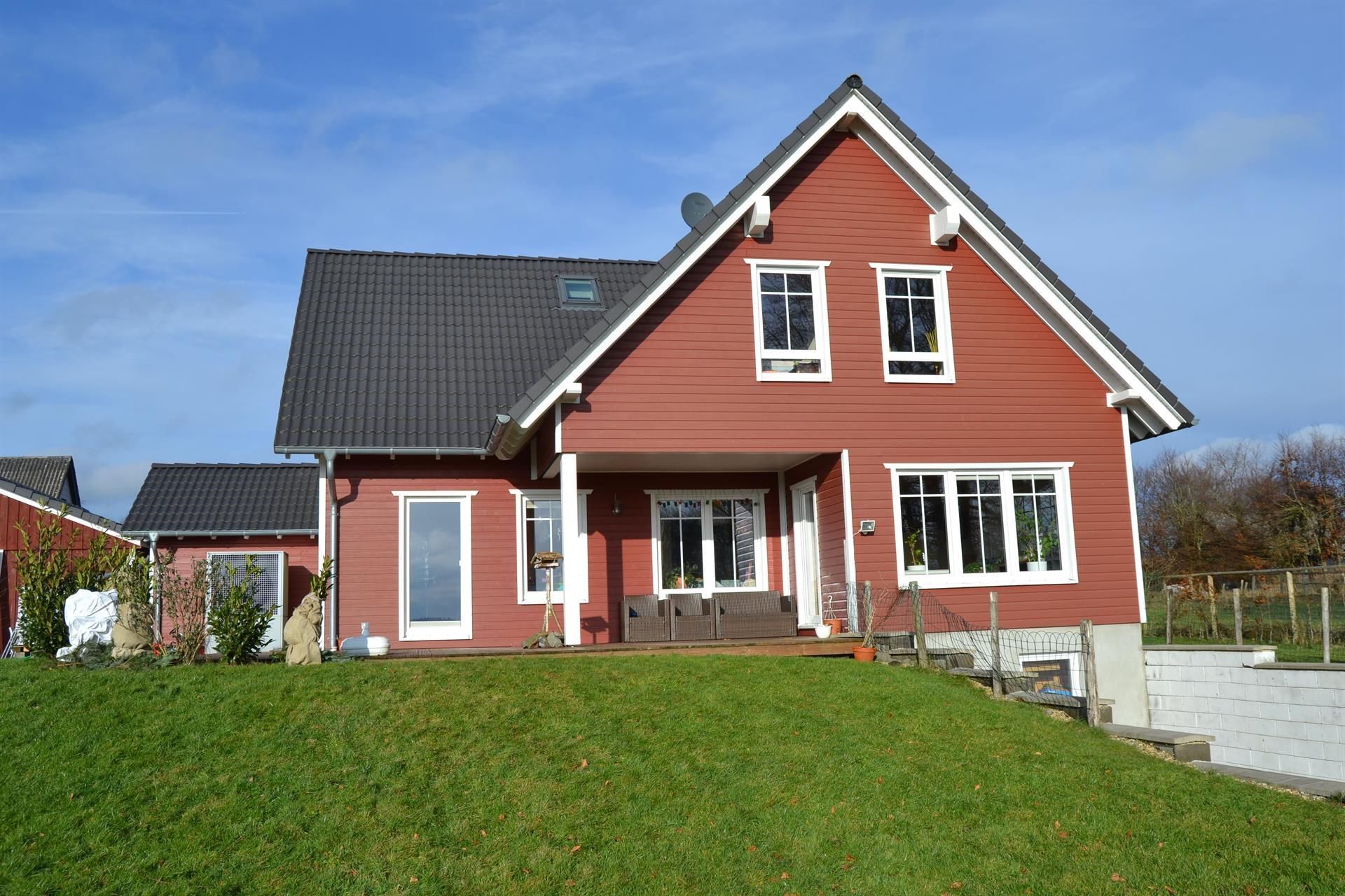 Ein großes rotes Haus steht auf einem grasbewachsenen Hügel