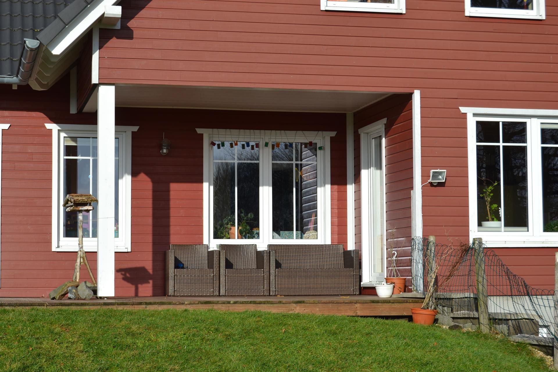 Ein rotes Haus mit weißen Fenstern und einer Veranda