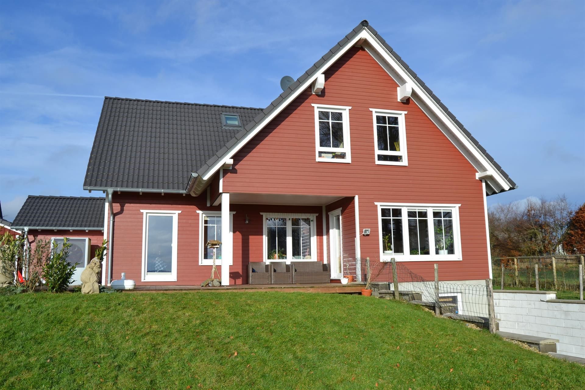 Ein großes rotes Haus liegt auf einem üppig grünen Hügel