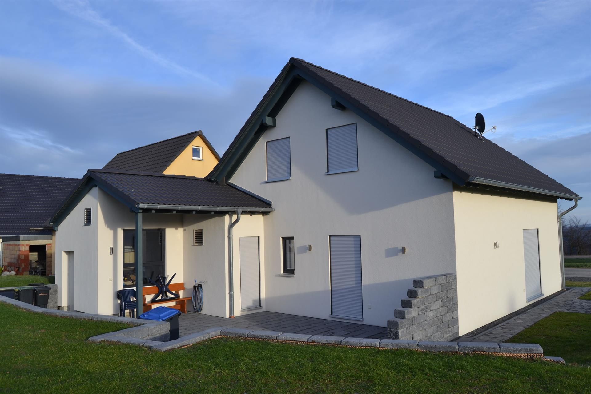 Ein weißes Haus mit einem schwarzen Dach und einem gelben Dach