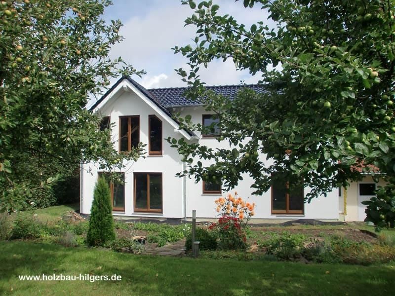 Ein weißes Haus mit einem blauen Dach ist von Bäumen umgeben