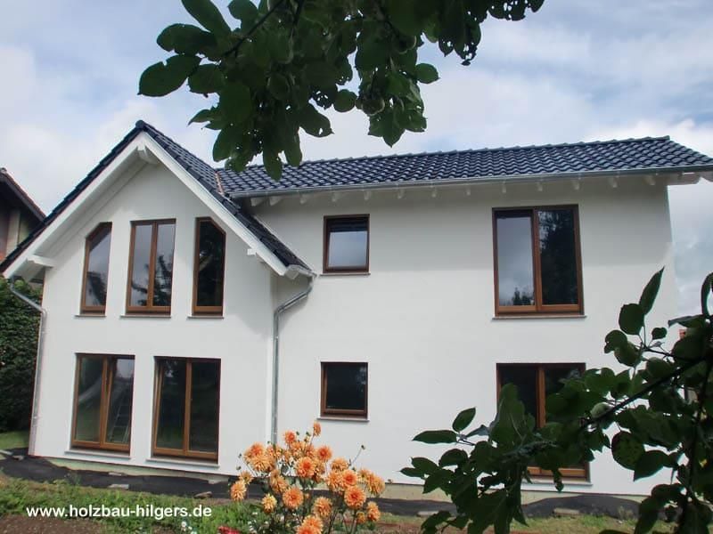 Ein weißes Haus mit schwarzem Dach und einem Baum davor