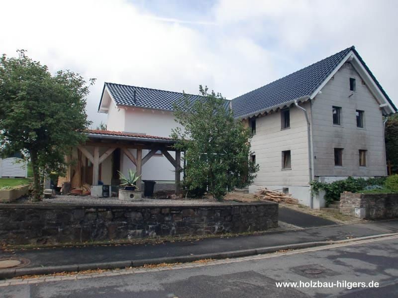 Ein weißes Haus mit einem schwarzen Dach und einer Steinmauer
