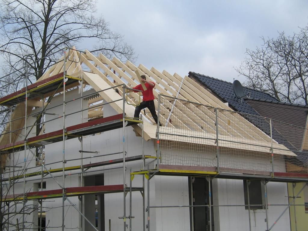 Ein Mann in einem roten Hemd arbeitet auf dem Dach eines Hauses
