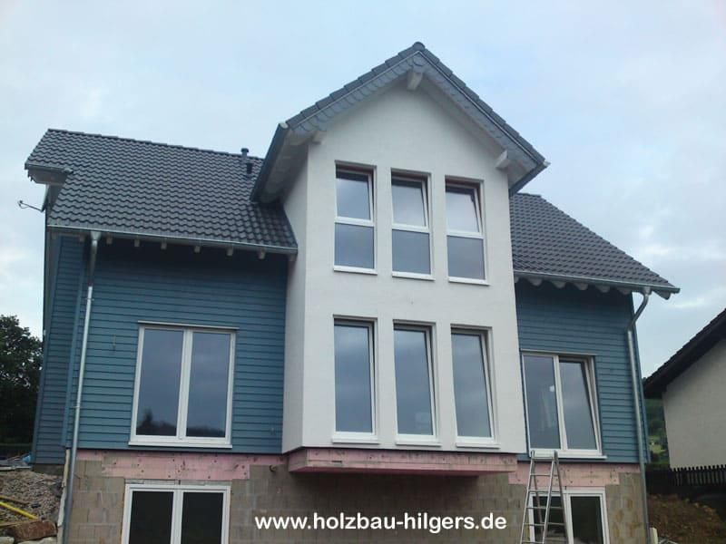 Ein blau-weißes Haus mit der Website www.holzbau-hilgera.de