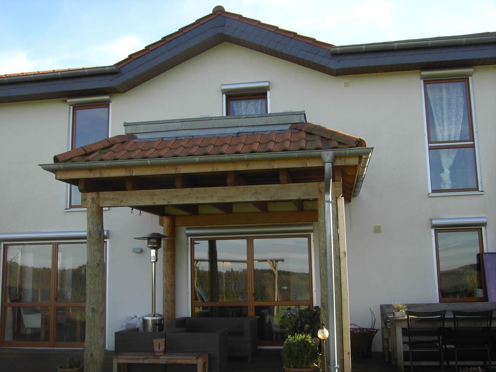 Ein weißes Haus mit einer Holzveranda und einem Dach