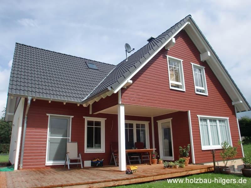 Ein rotes Haus mit einem schwarzen Dach und einer Satellitenschüssel auf dem Dach