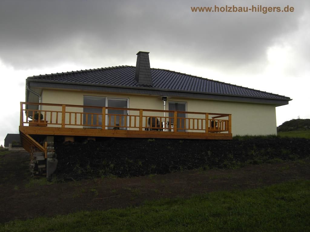 Ein Haus mit Holzterrasse und die Website www.holzbau-hilgers.de