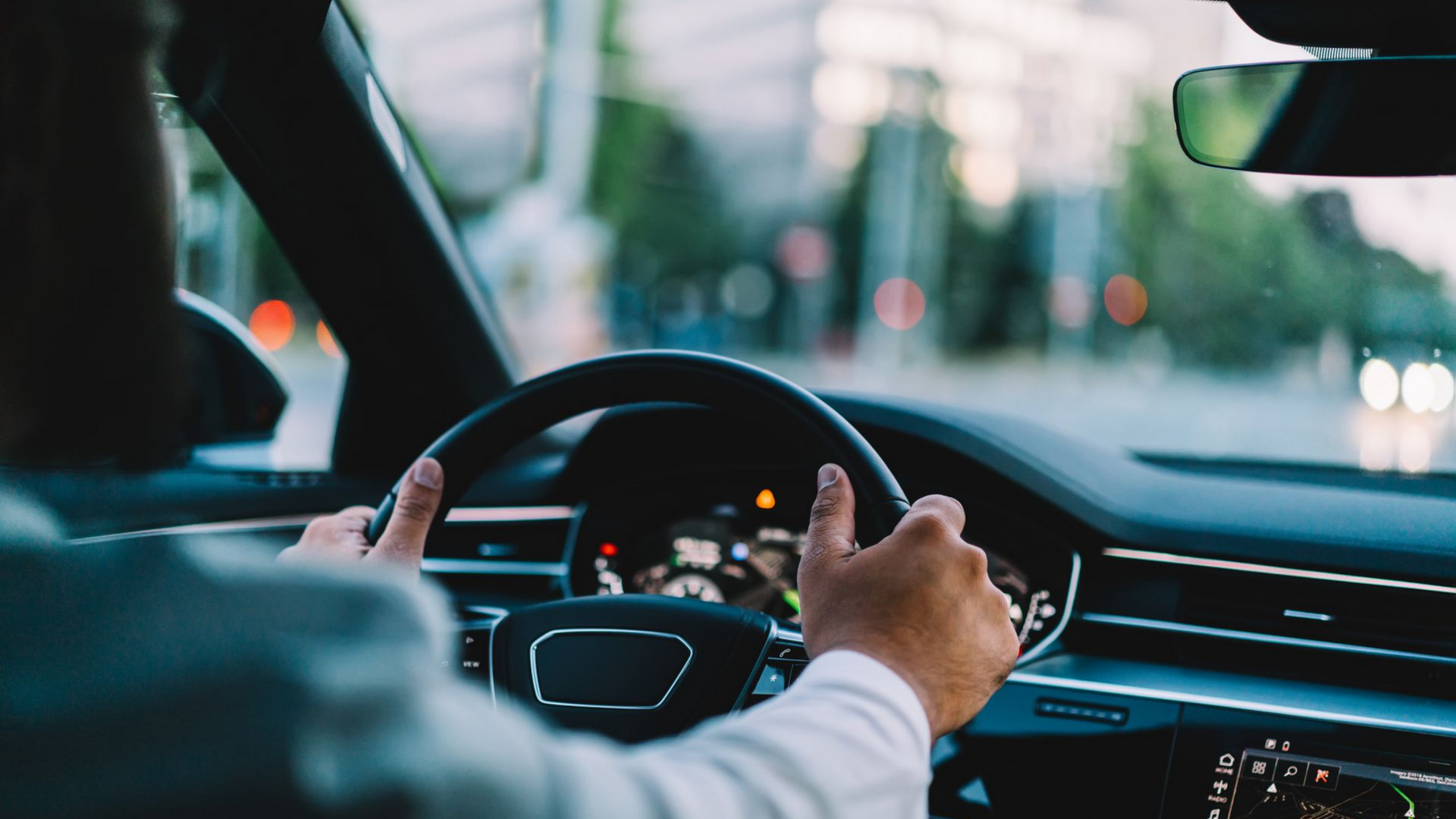 Une personne au volant d'une voiture, les mains sur le volant.