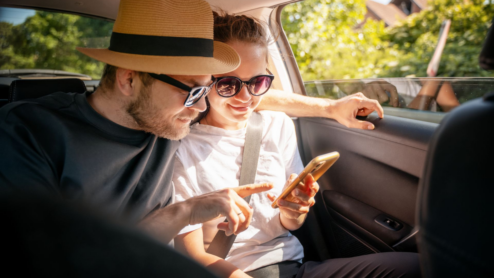 Deux personnes dans une voiture, l'homme regarde le téléphone de la femme.