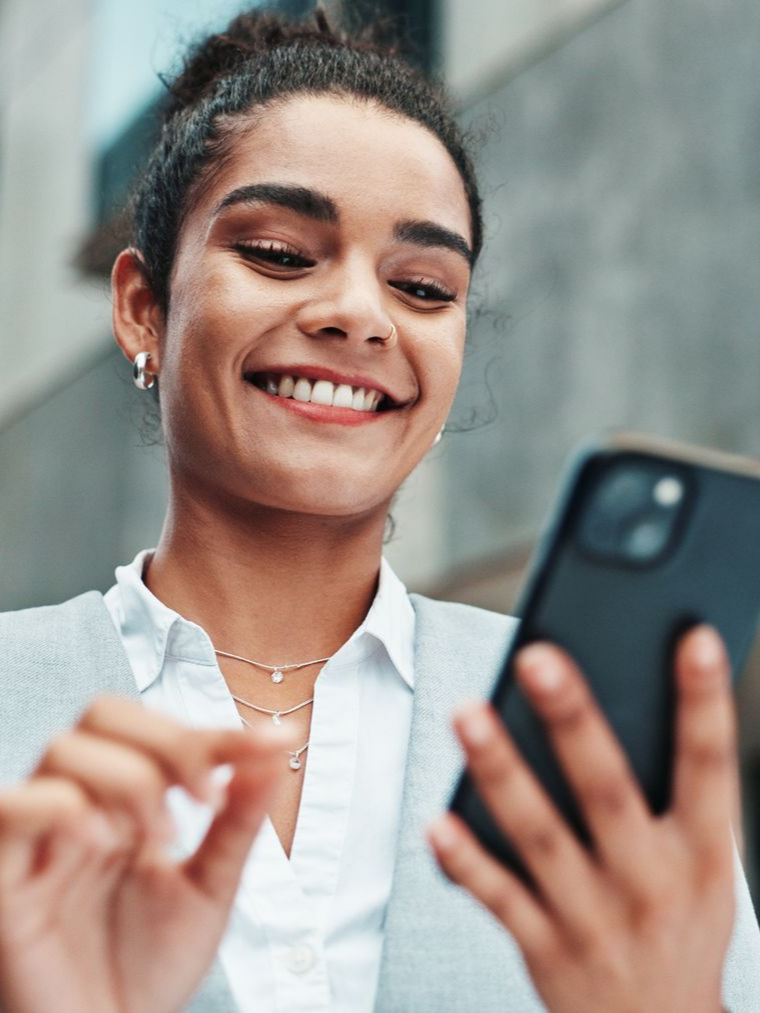 Une femme d'affaires regarde son téléphone et sourit.