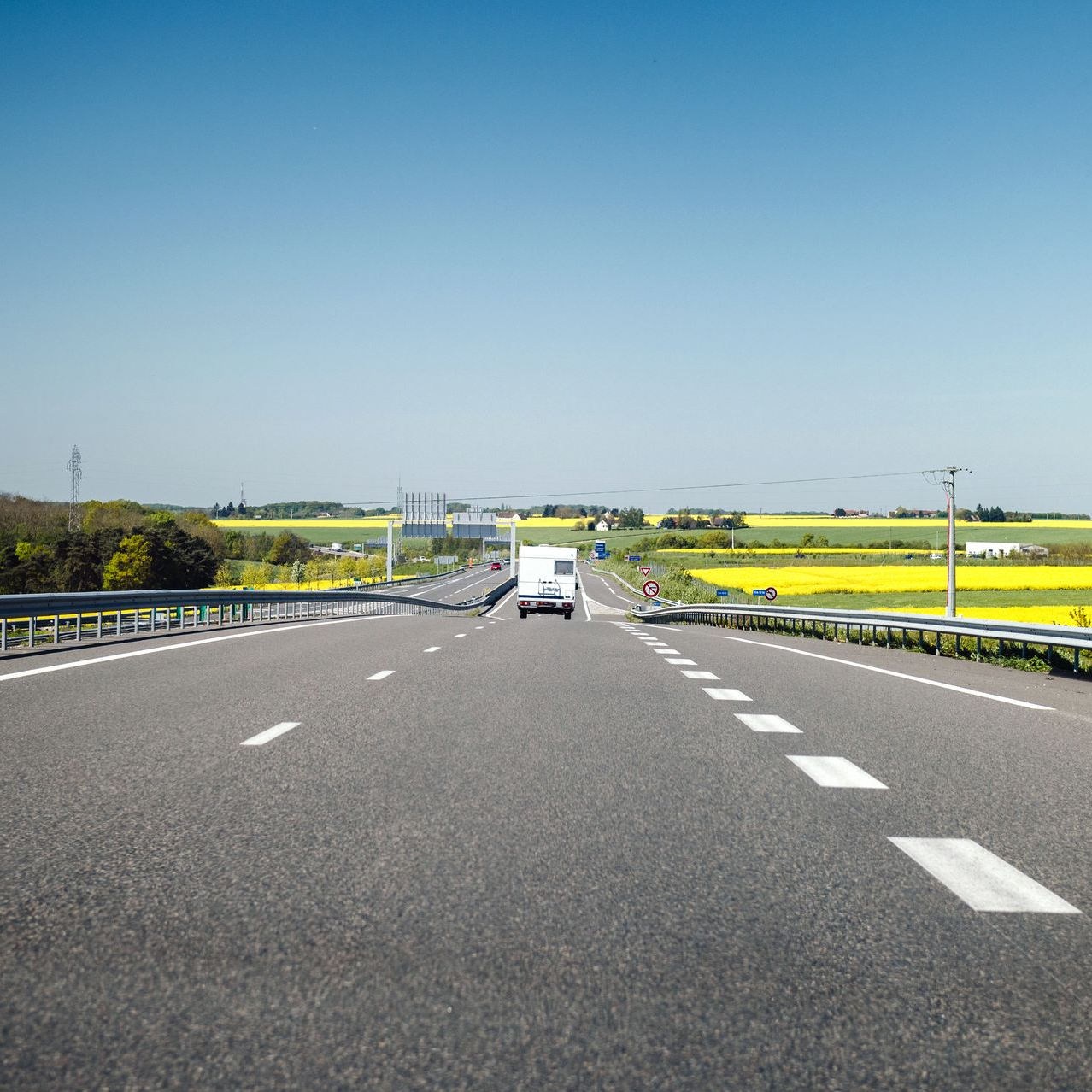 Autoroute entourée de champs de colza.