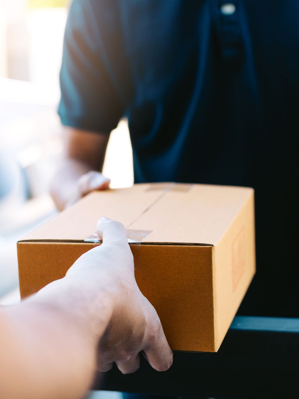 Un livreur remet en main un colis.