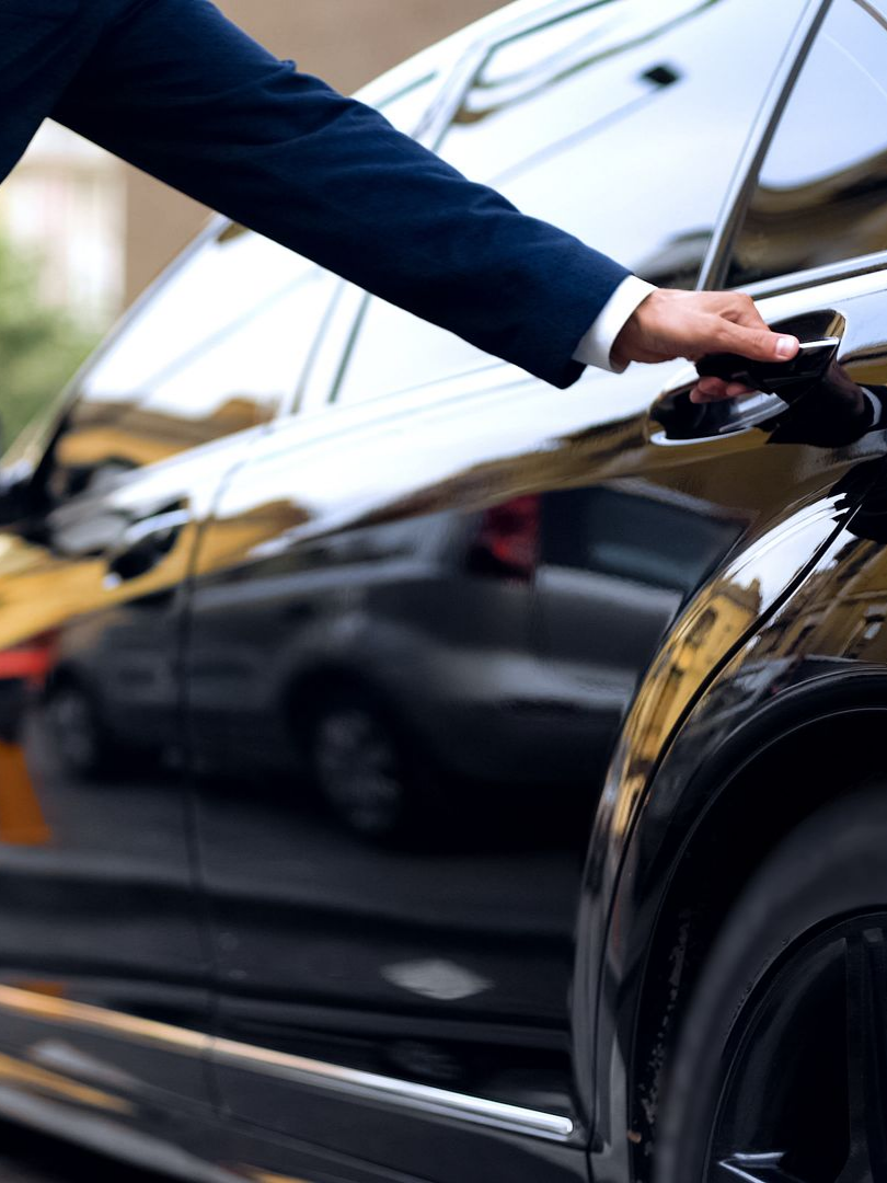 Une main sur la poignée d'une portière d'une voiture luxueuse.