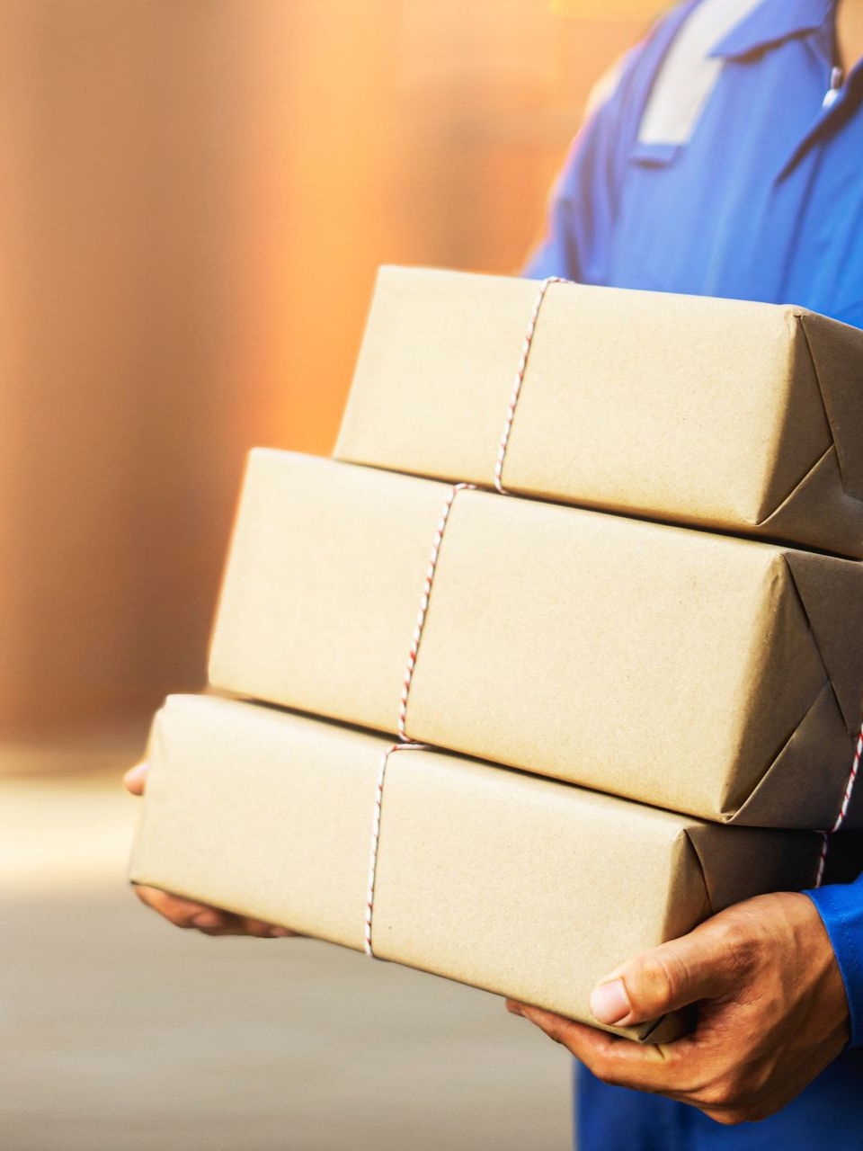 Un livreur tient 3 petits colis dans les mains.