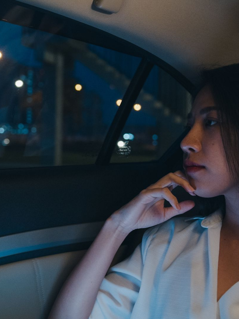 Une femme pensive à l'arrièrre d'un véhicule.