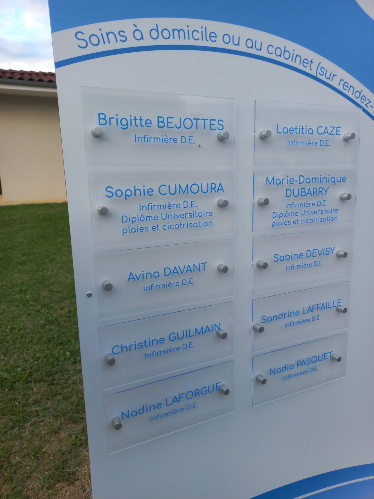 Panneau d'affichage extérieur français avec plaques blanches et texte bleu.