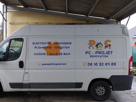 Une camionnette PC PROJET blanche est garée sous un abri, avec le logo de l'entreprise et ses coordonnées sur les côtés.