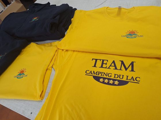 Maillots d'équipe jaunes et bleu marine avec l'inscription TEAM CAMPING DU LAC imprimée dessus.