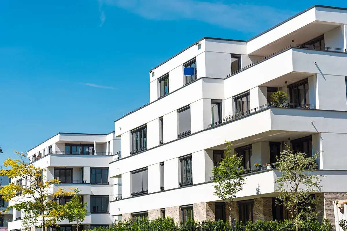 Ein großes weißes Wohnhaus mit einem blauen Himmel im Hintergrund.