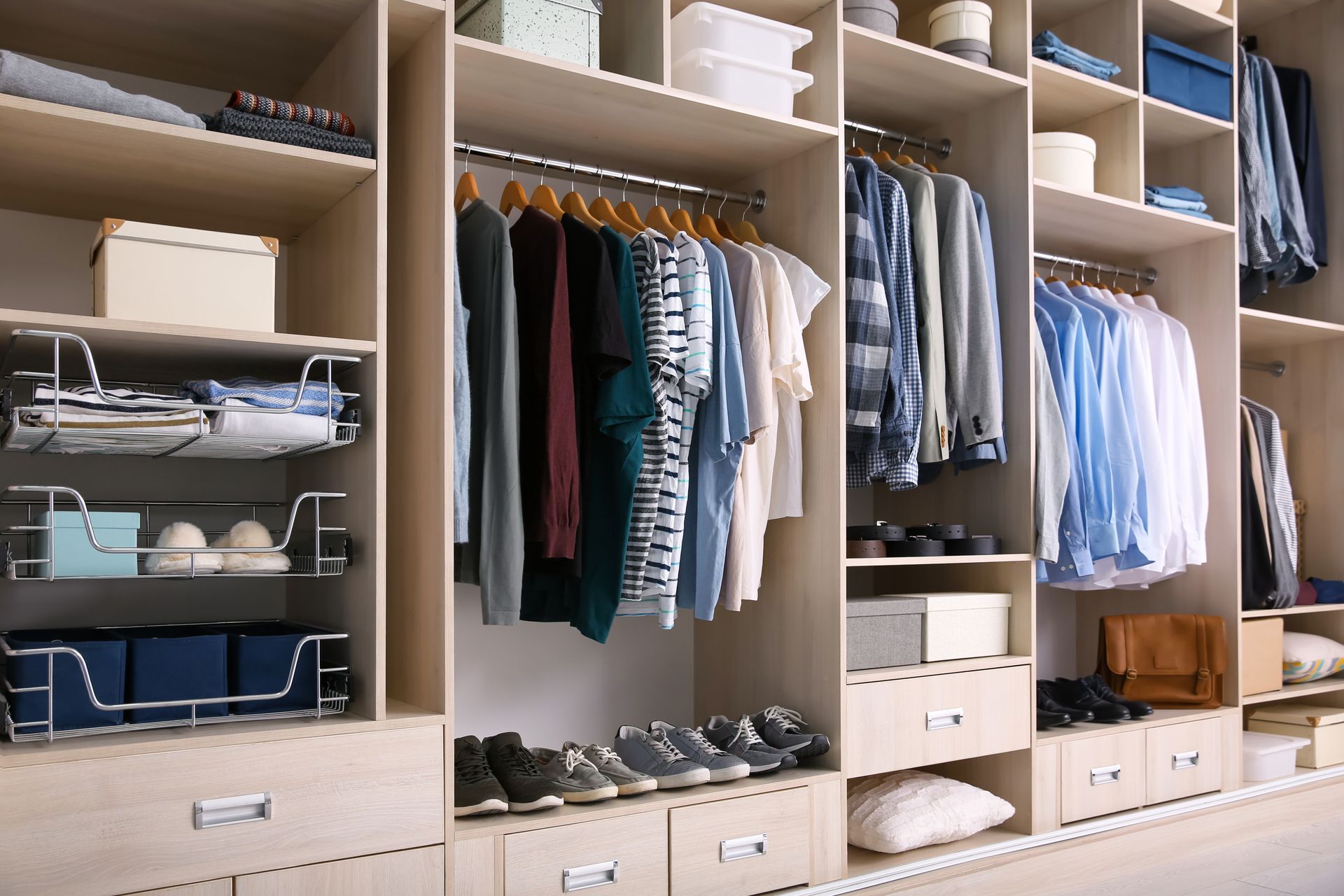 Placard ouvert avec vêtements, chaussures et boîtes de rangement soigneusement rangés dans une chambre.